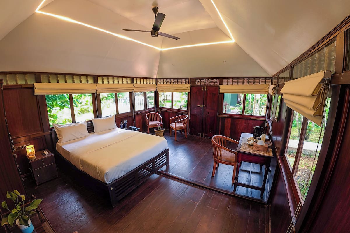 A bedroom with a bed, bedside table, chair, and a desk with a chair.