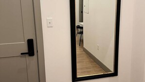 A hallway with a door on the left and a mirror on the right. - Brick & Bed - Luxury Downtown Loft (St. Louis)