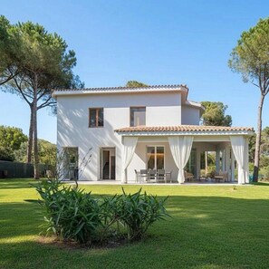 Une maison à deux étages avec un patio couvert, une pelouse et des arbres.