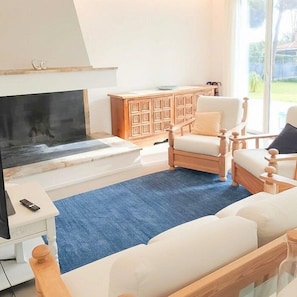 Ein Wohnzimmer mit Kamin, einer Couch, einem Sessel, einem Holzschrank und einem Fernseher.