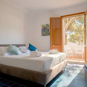 Une chambre d’hôtel avec un lit, une porte donnant sur un balcon et un tableau au mur.