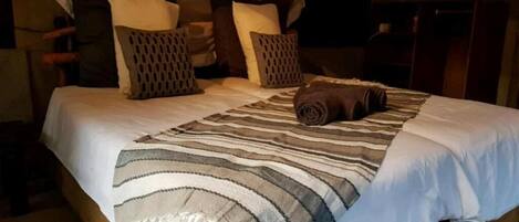 Un lit avec une couverture à rayures, plusieurs oreillers et une serviette enroulée.
