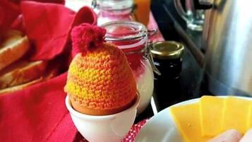 A breakfast setting with a knitted item on a white plate, a glass jar, and a metal container.