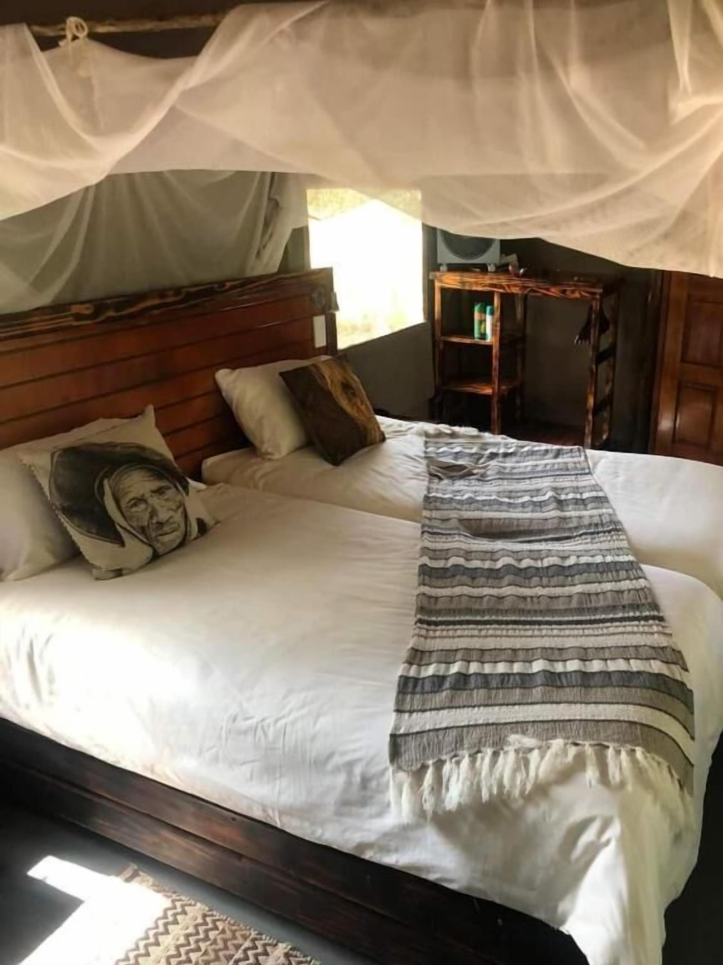 A bed with a canopy, pillows, a striped blanket, and a wooden headboard.