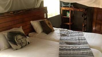 A bed with a canopy, pillows, a striped blanket, and a wooden headboard.