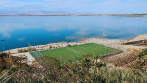 Un court de tennis offrant une vue dégagée sur le paysage environnant et sur une étendue d’eau.
