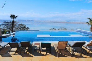 Una piscina con sillas de descanso y vistas a un cuerpo de agua.