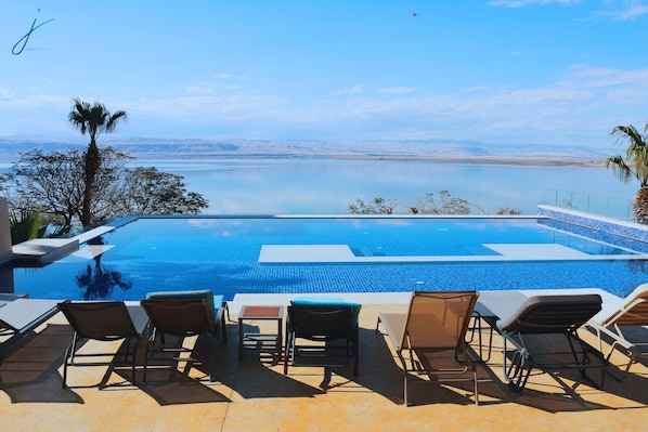 A swimming pool with lounge chairs and a view of a body of water.