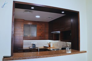 Une cuisine avec des meubles en bois, un plan de travail en granit, un évier en acier inoxydable et une cuisinière intégrée.