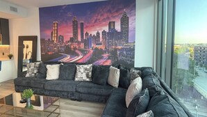 Uma sala de estar moderna com um grande mural da paisagem urbana, um sofá seccional e uma mesa de centro de vidro.