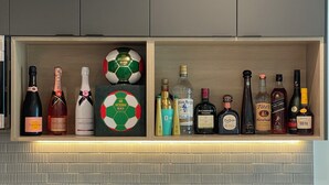 Cozinha com bancada, pia, planta em vaso e prateleira com diversos frascos.