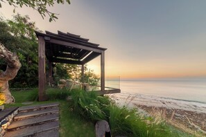 Una pérgola de madera con vistas al océano al atardecer.