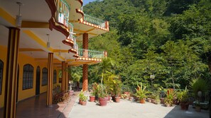 A building with a yellow facade, multiple balconies, and potted plants. - Rishikesh sadan- the spiritual Retreat  (Rishikesh)
