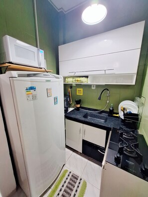 Eine kleine Küche mit Kühlschrank, Mikrowelle, Spüle und Herd.