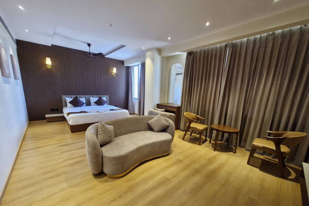 A modern hotel room with a bed, a sofa, a desk, and a chair.