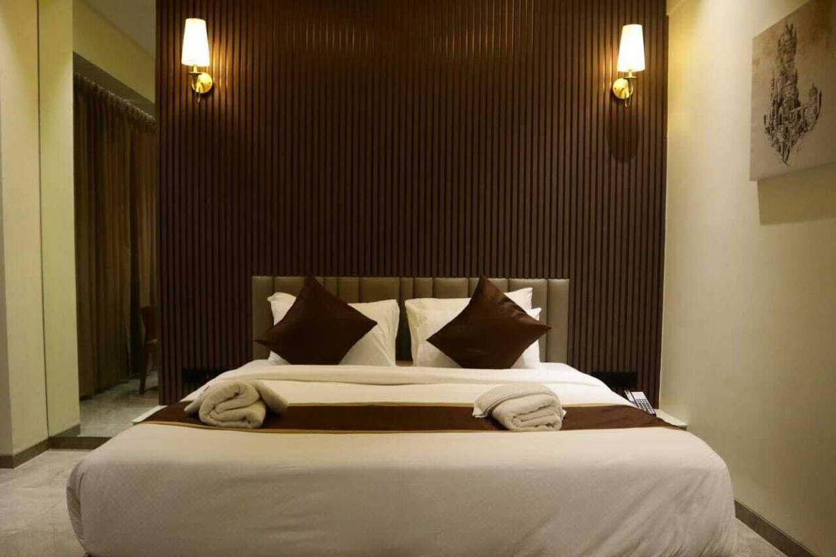 A hotel room with a large bed, two wall-mounted lamps, and a painting on the wall.