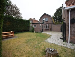 A residential property with a brick house, a gravel driveway, and a wooden bench. - Seaside Escape With Large Garden (Oostkapelle)