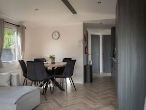 A modern interior with a dining table, chairs, a clock, and a view of a hallway. - Cozy Heinkenszand Retreat (Heinkenszand)