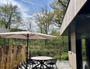 An outdoor patio with a round table, chairs, and a large umbrella. - Modern Coastal Stay in Zoutelande (Zoutelande)