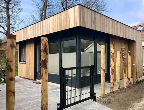 A modern building with a wooden exterior, large windows, and a black metal gate. - Modern Coastal Stay in Zoutelande (Zoutelande)