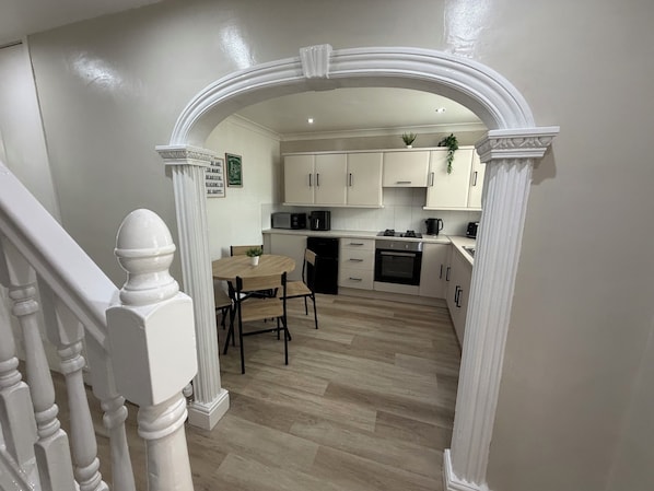 Una cocina moderna con armarios blancos, una mesa de comedor y una escalera con barandilla blanca.