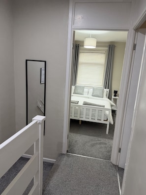 Un dormitorio con cama, lámpara de noche y ventana con persianas.