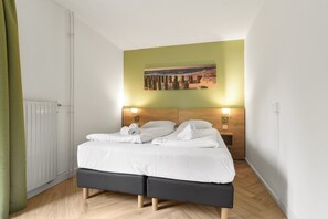 Ein Schlafzimmer mit Bett, Kopfteil, Wandgemälde und Nachttisch mit Lampe.