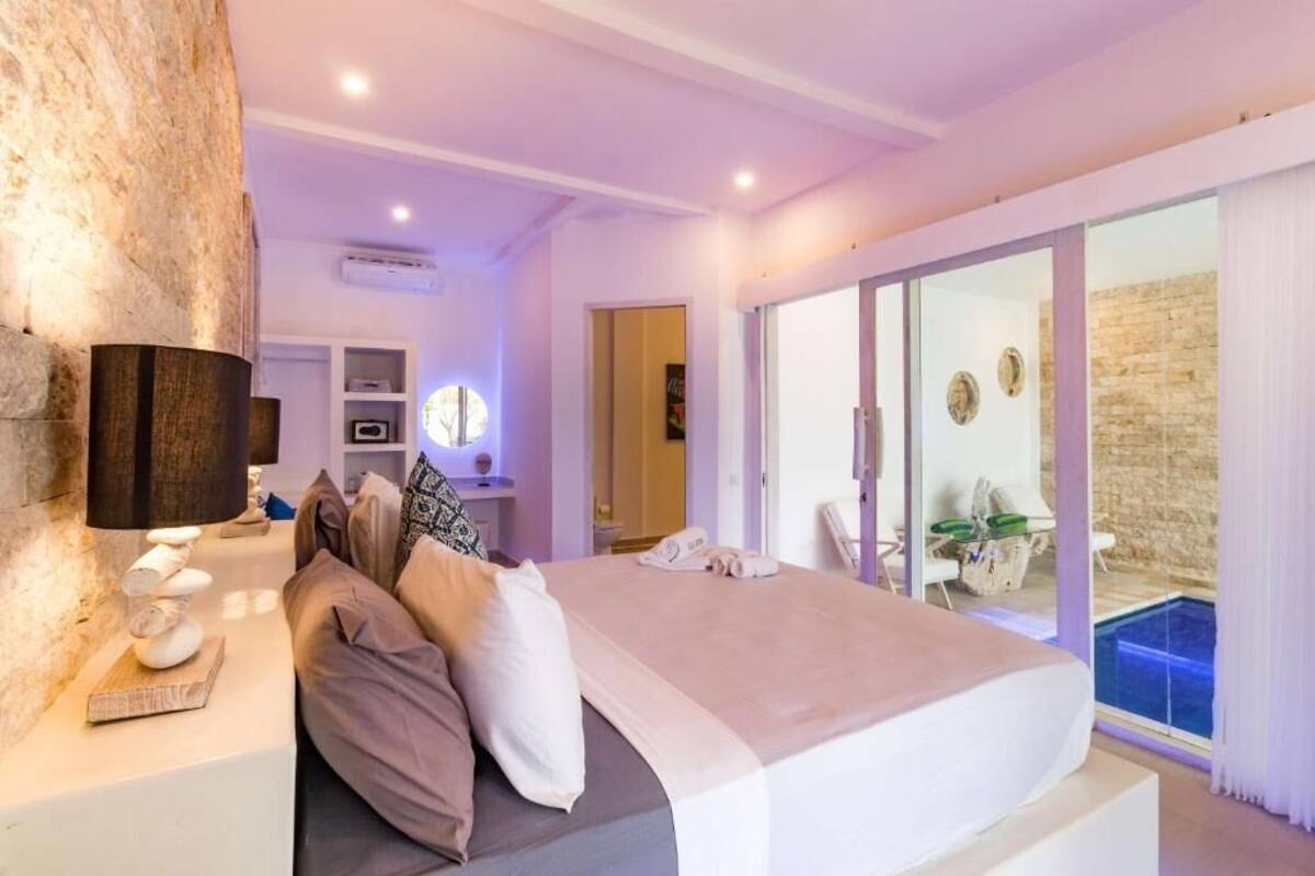 Ein modernes Schlafzimmer mit Bett, Nachttisch und Blick auf einen Außenpool.