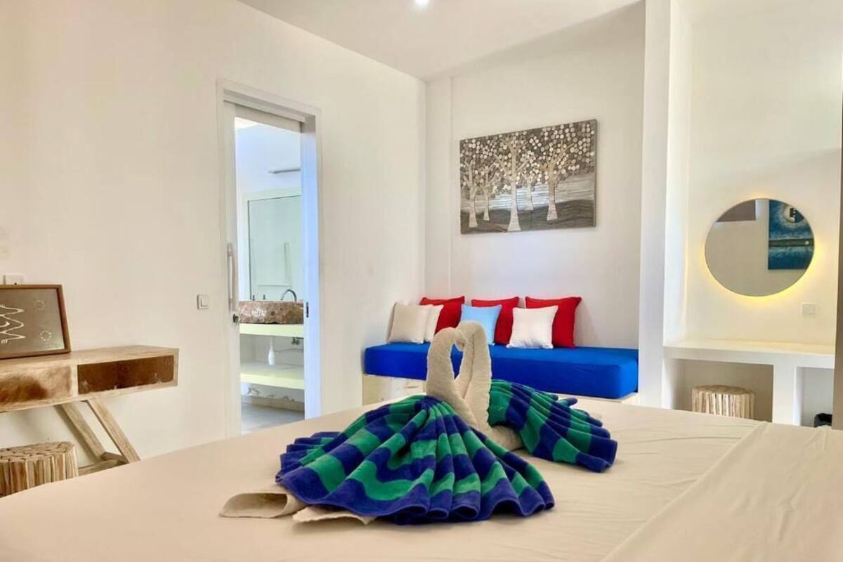 Ein Hotelzimmer mit einem Bett, einem blauen Sofa, einem Gemälde und einem runden Spiegel.