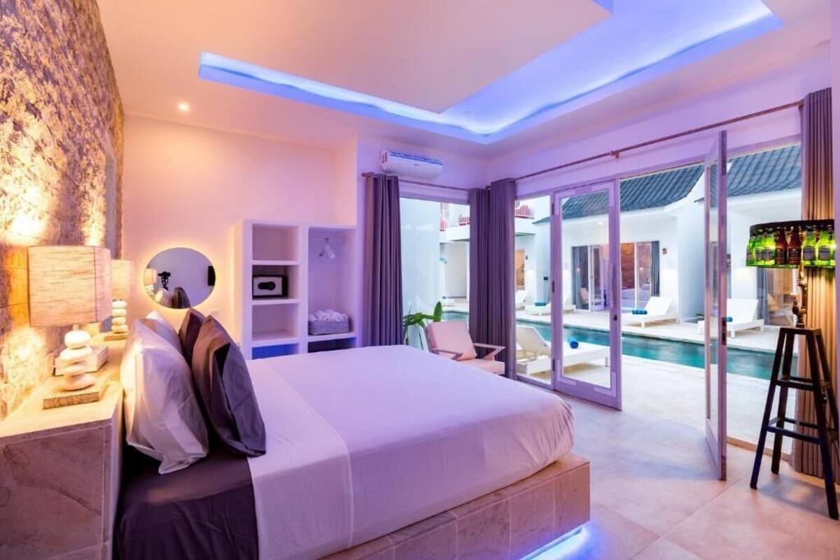 Ein modernes Hotelzimmer mit einem großen Bett, einem Schreibtisch, einem Sessel und Blick auf den Pool, sowie einer Treppe.