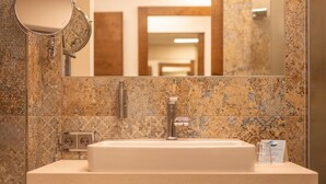 Un baño con lavamanos de mármol, un espejo y un mueble de madera.