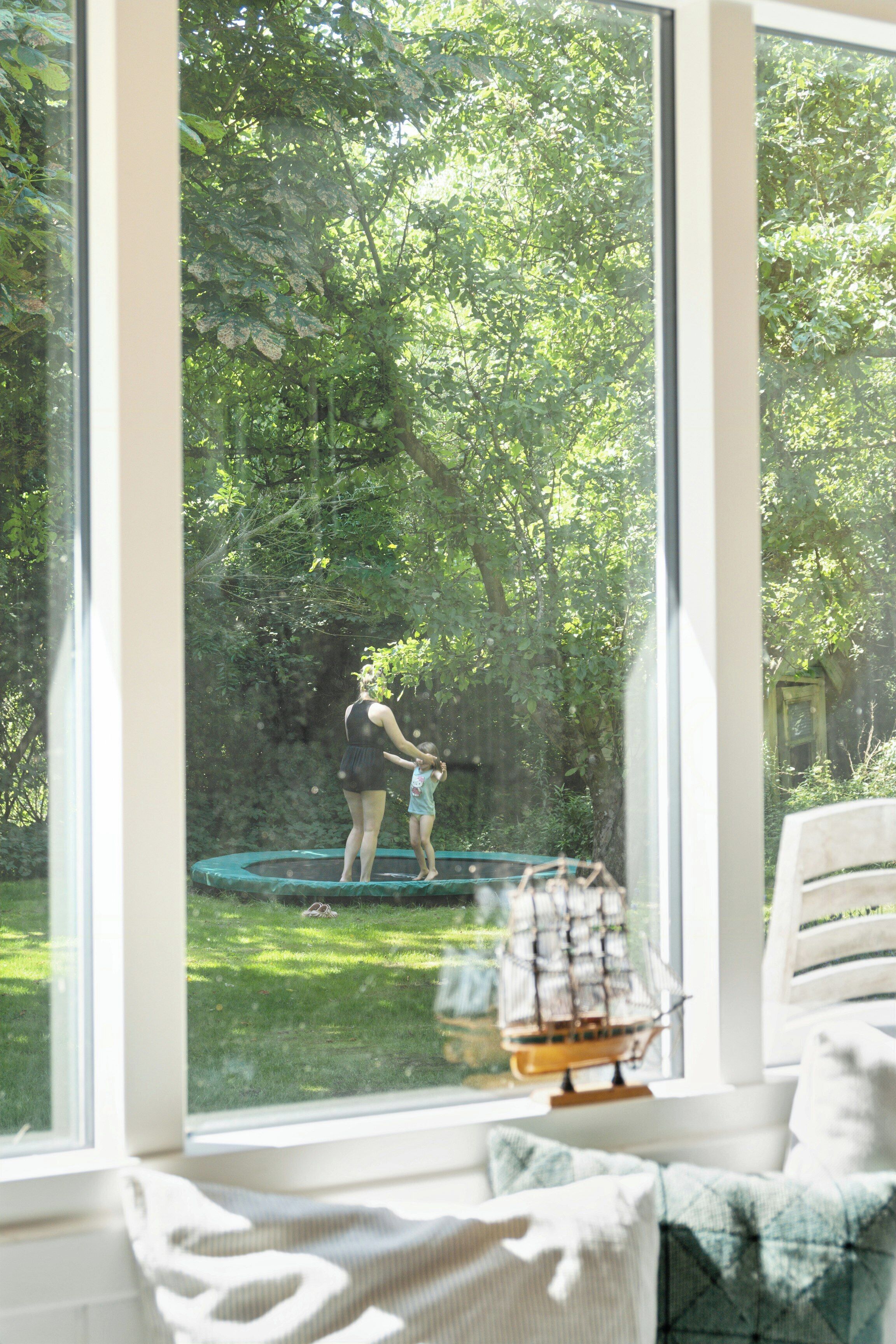 A room with a large window, a bed, and a view of a garden.