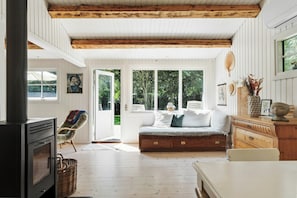 Ein gemütliches Zimmer mit Kamin, einer Bank und einem Esstisch.
