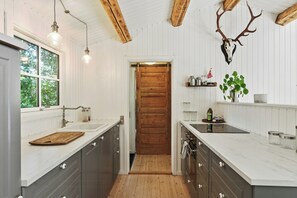 Une cuisine avec des poutres en bois, une porte en bois et un crâne de cerf accroché au mur.
