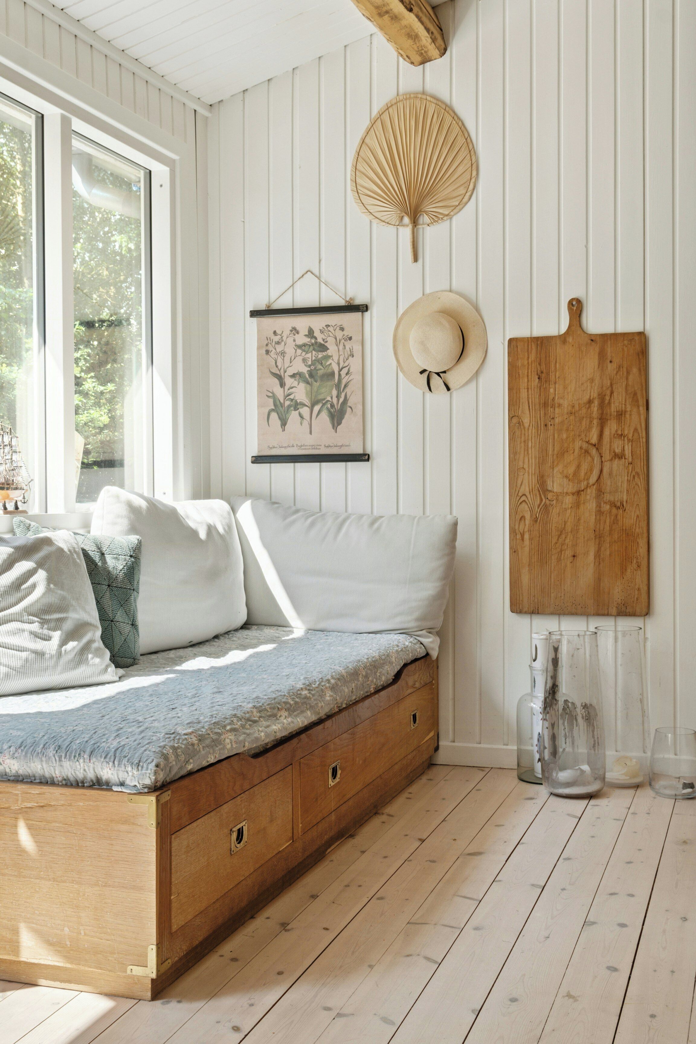 A bed with storage drawers, a wooden headboard, a wall-mounted fan, a framed botanical illustration, and a wooden board.