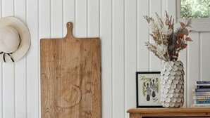 Una tabla de madera, un florero con plantas secas y un aparador con cajones.