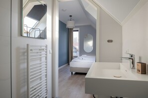 Ein modernes Hotelzimmer mit einem großen Bett, einem weißen Waschbecken und einem Oberlicht.