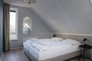 Ein Schlafzimmer mit Bett, Nachttisch, Spiegel und einem Fenster mit Vorhängen.