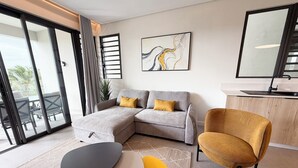 A modern living room with a grey sectional sofa, a yellow armchair, and a small round table. - Asmara Residence- 2 Bedroom,Grande Riviere Noire (Grande Riviere Noire)