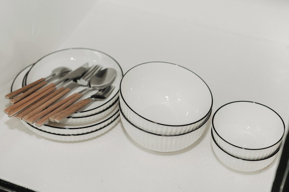 A white table with stacked plates, a bowl, and a cup.