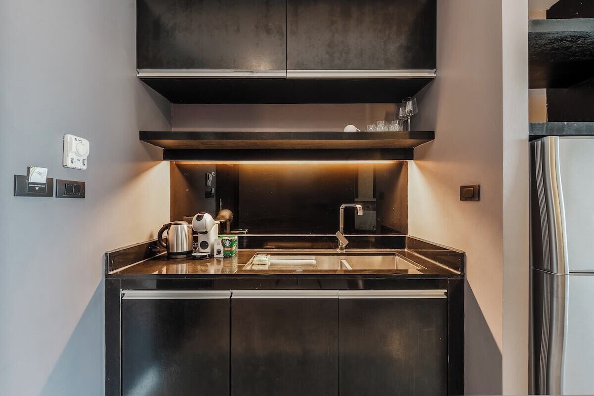 A modern kitchen with a stainless steel sink, a coffee maker, and a kettle.