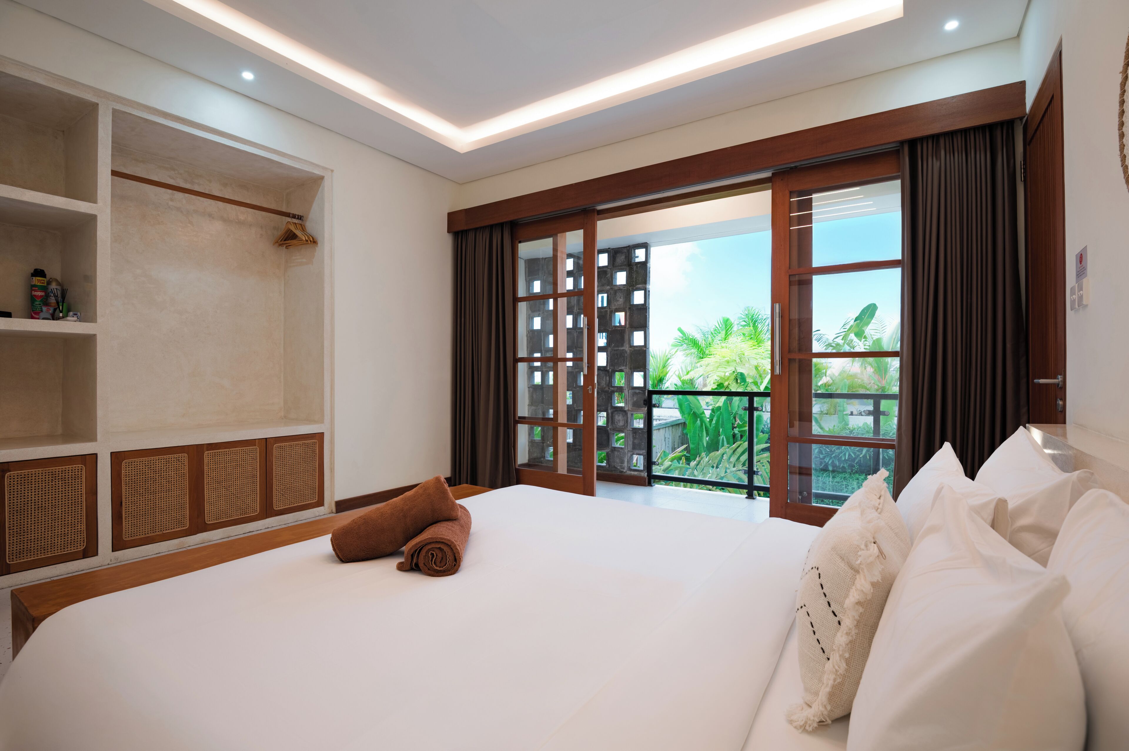 A hotel room with a large bed, a wardrobe, a balcony with a view, and a ceiling light.