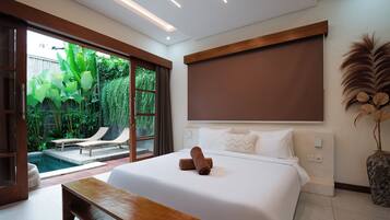 Habitación de hotel moderna con una cama grande, un banco, vista a una piscina y un ventanal corredizo que da a un jardín.