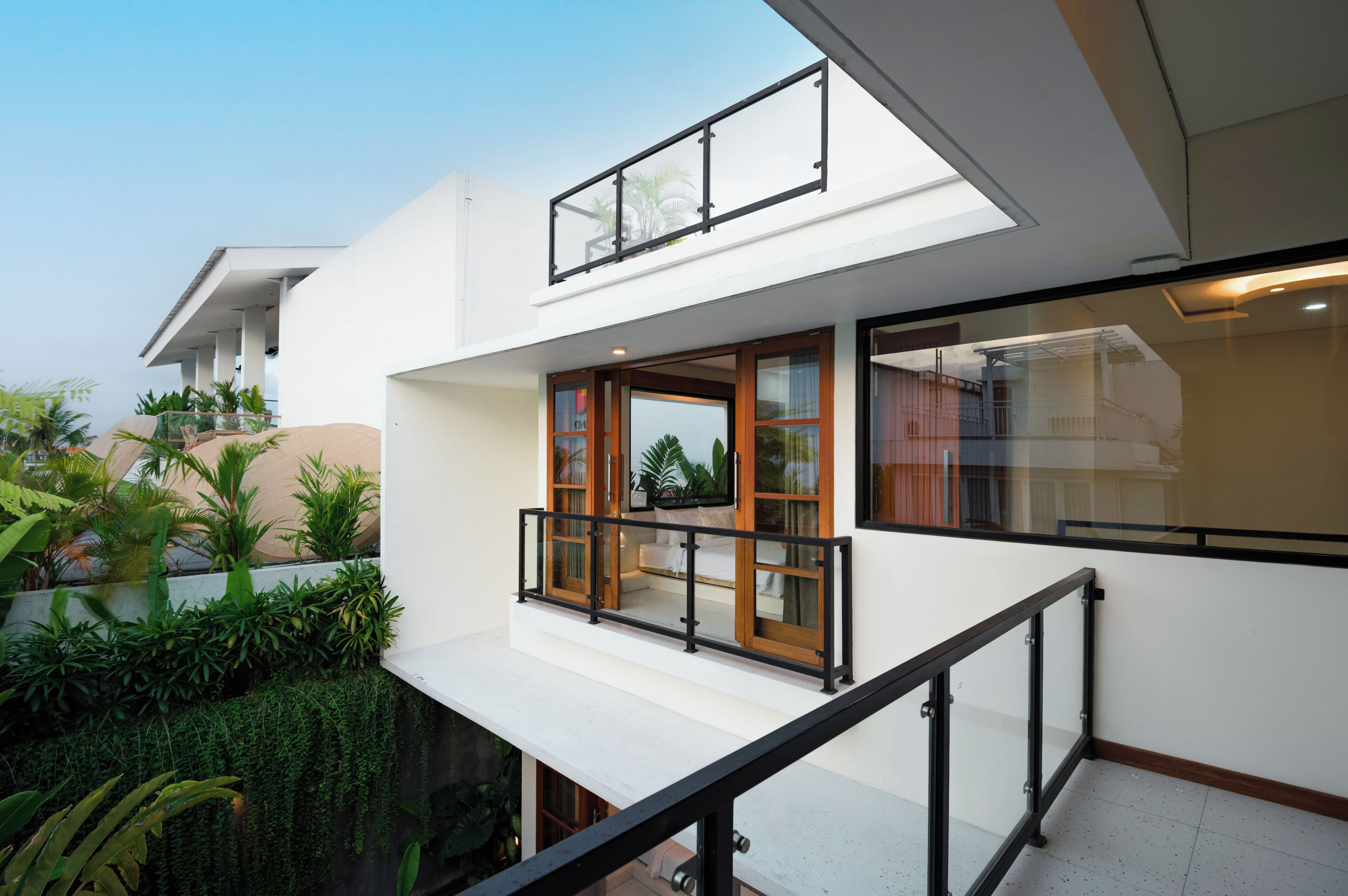 Una casa moderna de dos pisos con balcón, ventanas amplias y techo plano.