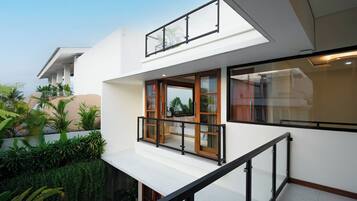 Una casa moderna de dos pisos con balcón, ventanas amplias y techo plano.