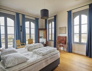 A bedroom with a large bed, two chairs, a desk, and a mirror. - Estate Stay With Natural Pool (Oostkapelle)