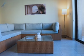 A living room with a sectional sofa, a glass coffee table, and a floor lamp.