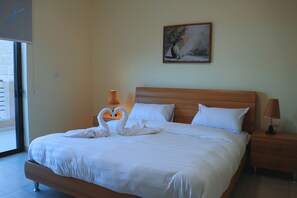 Una cama bien hecha con sábanas blancas, cabecera de madera y dos lámparas de noche.