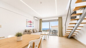 Ein modernes Wohnzimmer mit einem Holzesstisch, weißen Stühlen, einer Couch und einer Treppe.