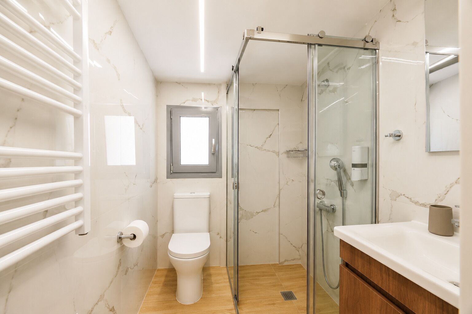 Une salle de bain comprenant des toilettes, une douche à parois de verre, un lavabo et un porte-serviettes.